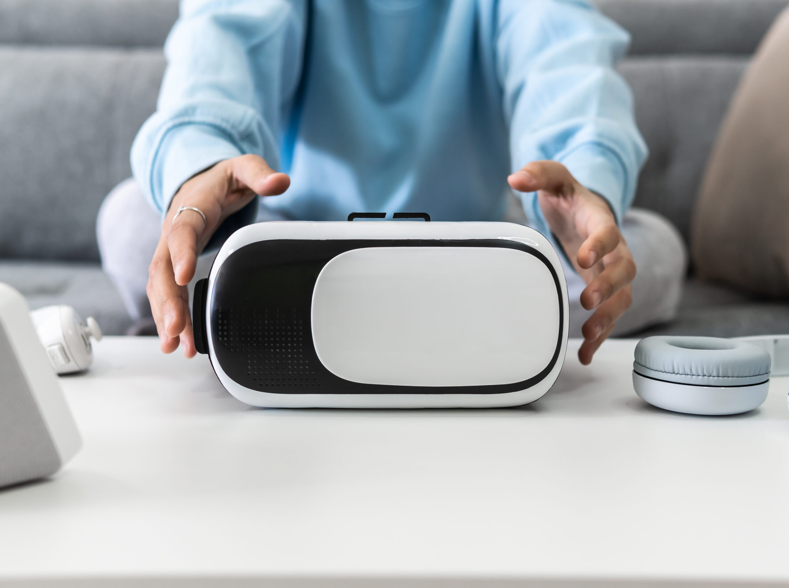 Female sitting on the couch picking up virtual reality glasses from the table